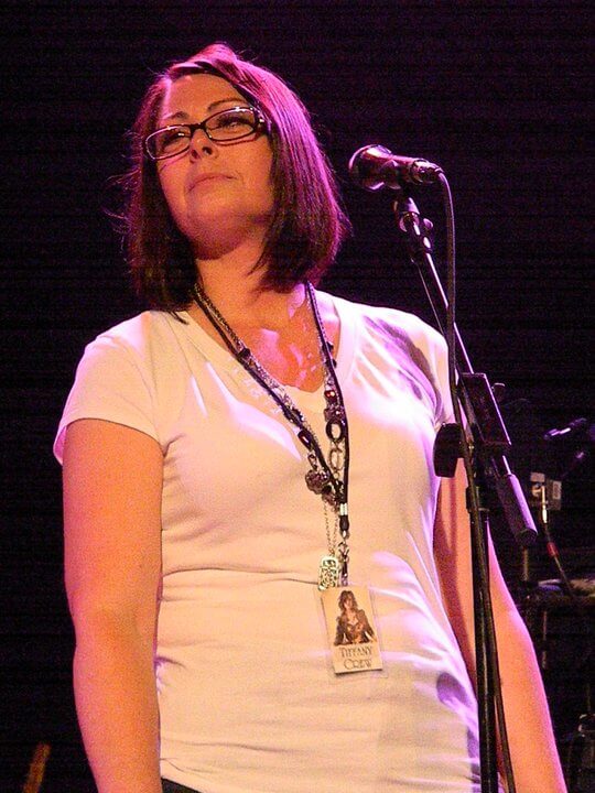 Josee Madison speaking on stage with a microphone, sharing insights on self-awareness and leadership